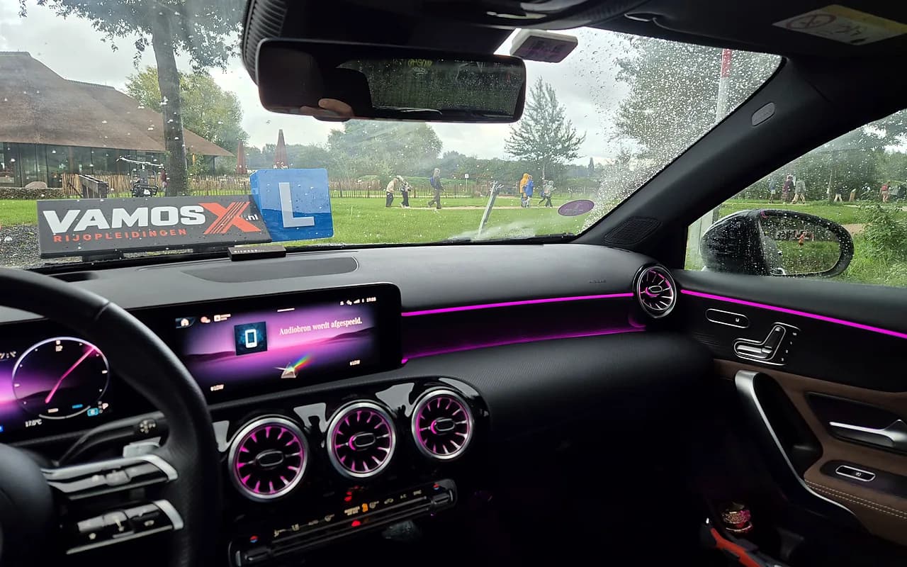 Het interieur van de Mercedes A180 met sfeerverlichting, en door de voorruit het VamosX-dakbord