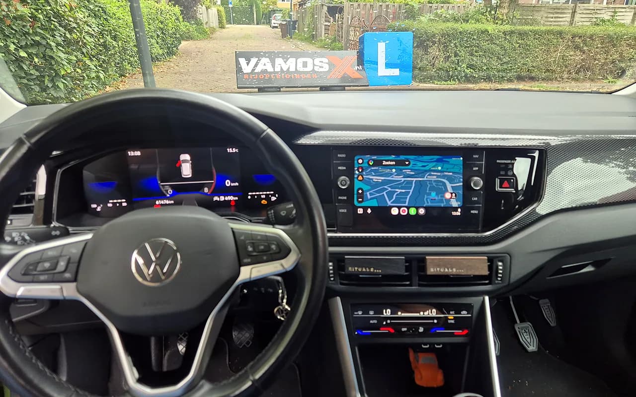 Het dashboard van onze Volkswagen schakel-lesauto, rechts de pedalen van de dubbele bediening en door de voorruit het VamosX-dakbord